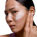 A woman using her ESK B Quenched moisturiser on her cheek. She swipes a good amount across her cheek to hydrate and moisturise her skin.
